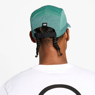 back view of the ciele athletics GOCap unisex running hat with a curved brim in silver pine color, on a model