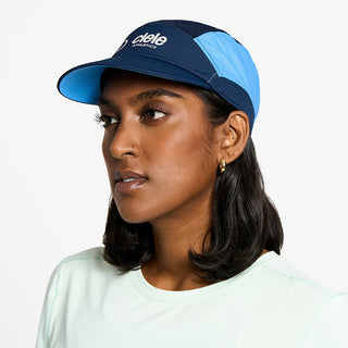side view of the ciele athletics FTSCap unisex running hat with a curved brim in indigo color, on a model